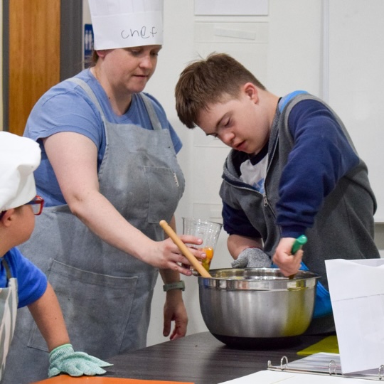 Cooking class teacher and student mixing fruit salad